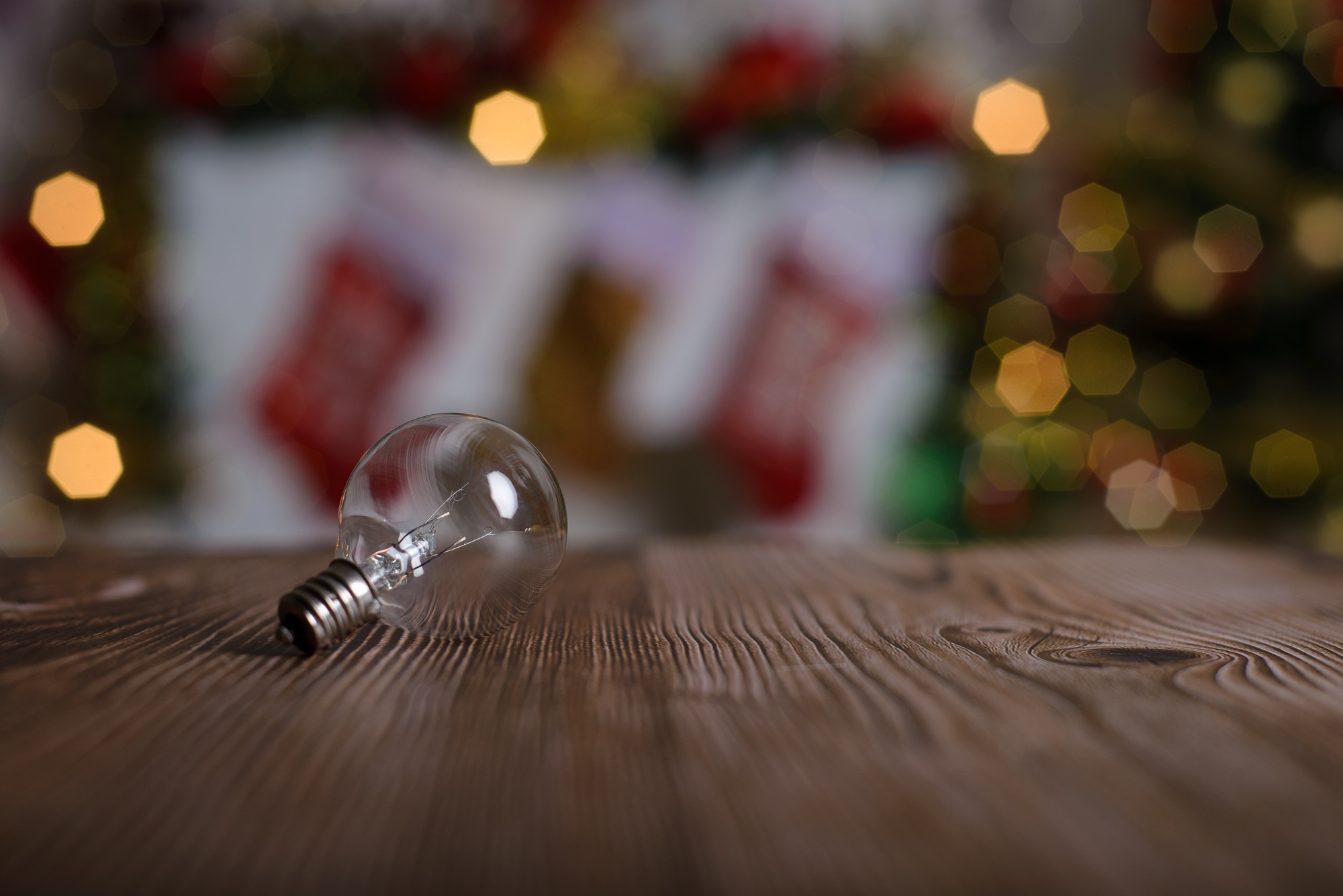 Burnt out light bulb on wooden table, christmas background. End concept.